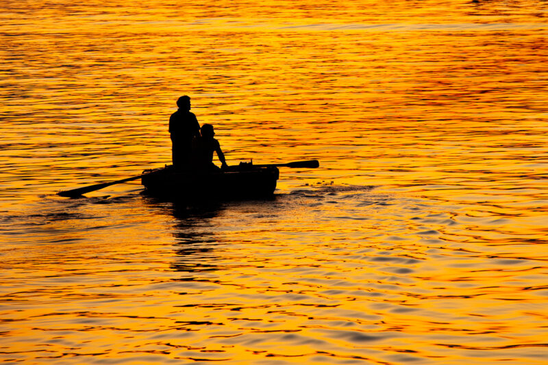 dos hombres en una barca a contraluz luz dorada