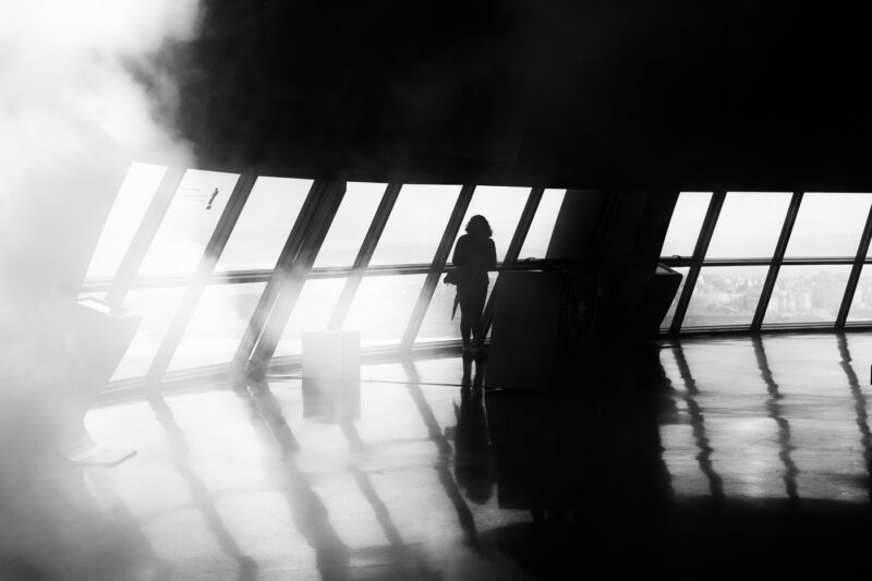 mujer a contraluz en mirador de cristal A Coruña niebla