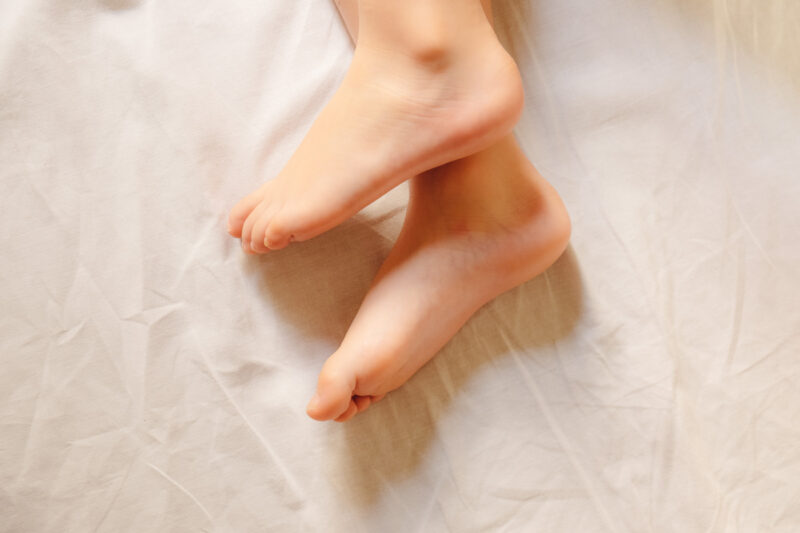 el factor humano pies de niño sobre sábana
