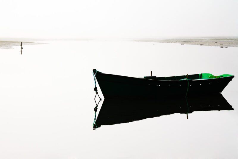 el mar y el espejo barca con reflejo en el agua con niebla