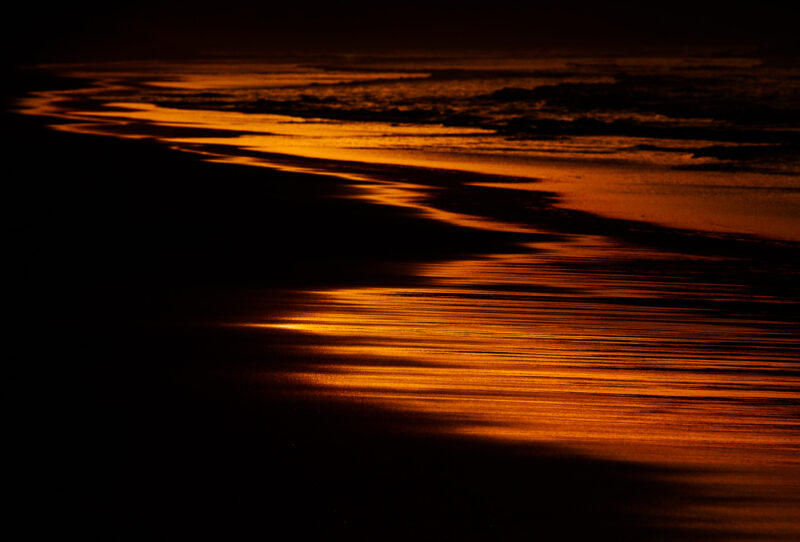 el mar y el espejo reflejo rojo del sol en la arena