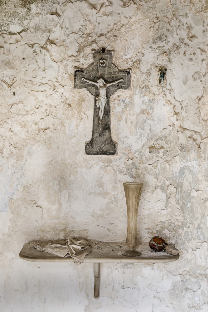 objetos encontrados interior de una cripta en cementerio con cruz y estante de madera con trapo y jarrón de cristal