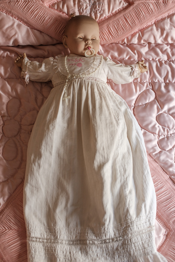 objetos encontrados muñeca con vestido blanco sobre una cama con colcha rosa