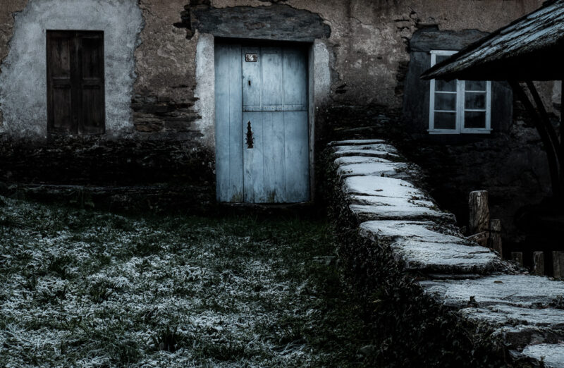 entrada de una casa de aldea con helada muro de piedra y puerta azul